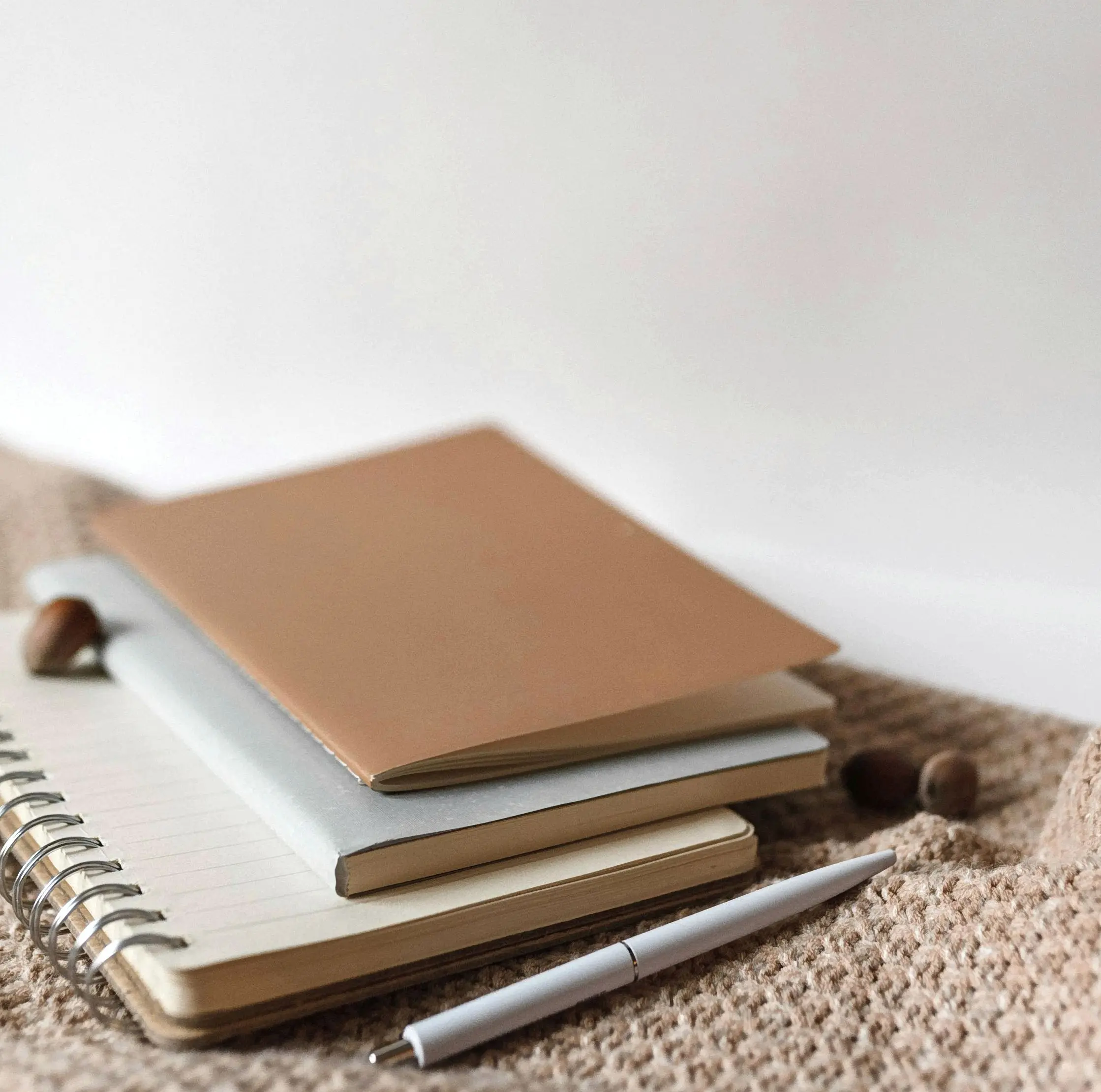 Trois carnets de notes artisanaux en tissu, faits main, posés sur une table – papeterie créative de Mallyana Création.