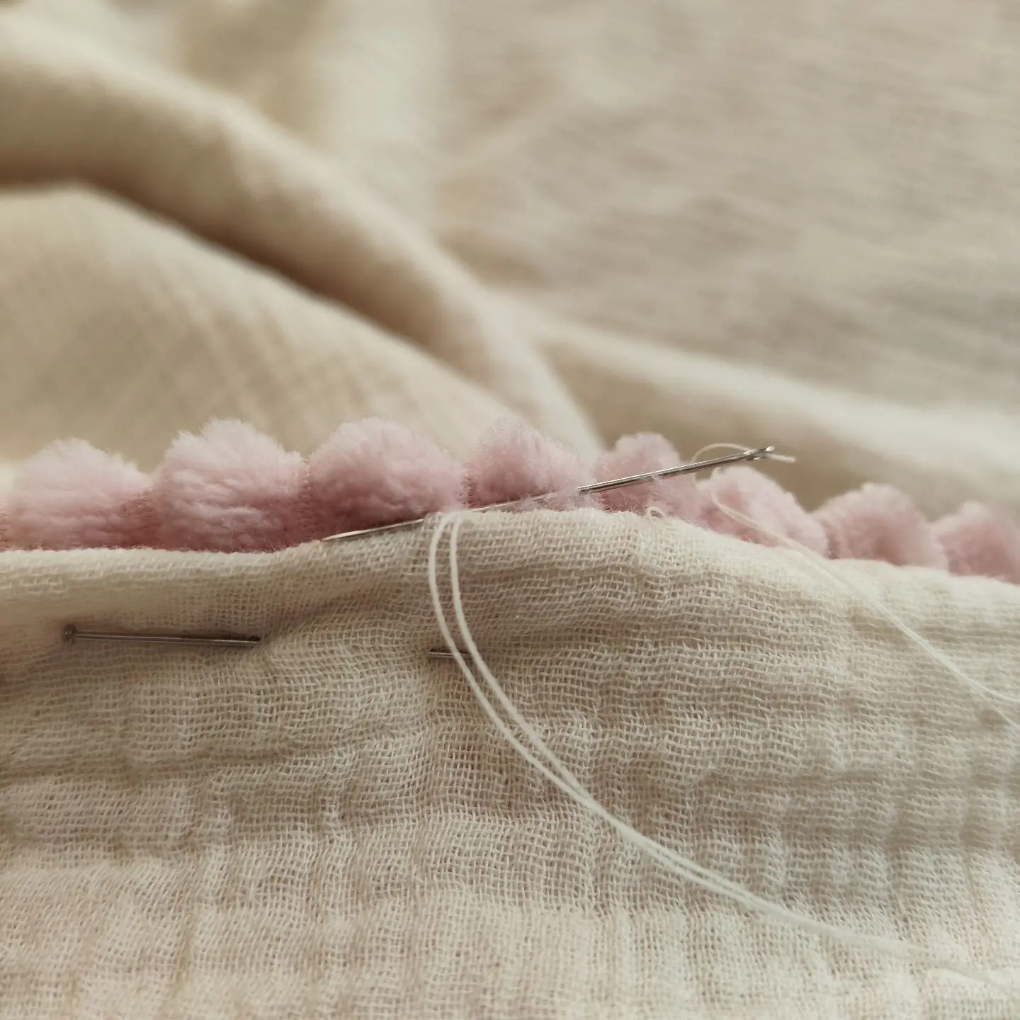 Gros plan détaillé sur une aiguille à coudre insérée dans un tissu, symbolisant le savoir-faire artisanal de Mallyana Création