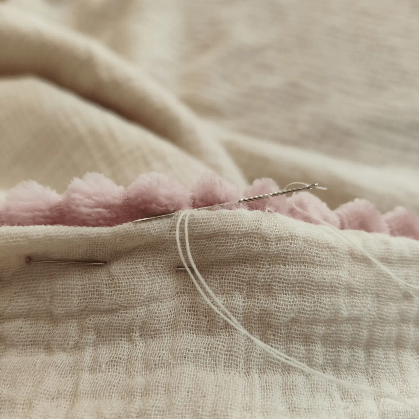 aiguille à coudre insérée dans un tissu, symbolisant le savoir-faire artisanal de Mallyana Création